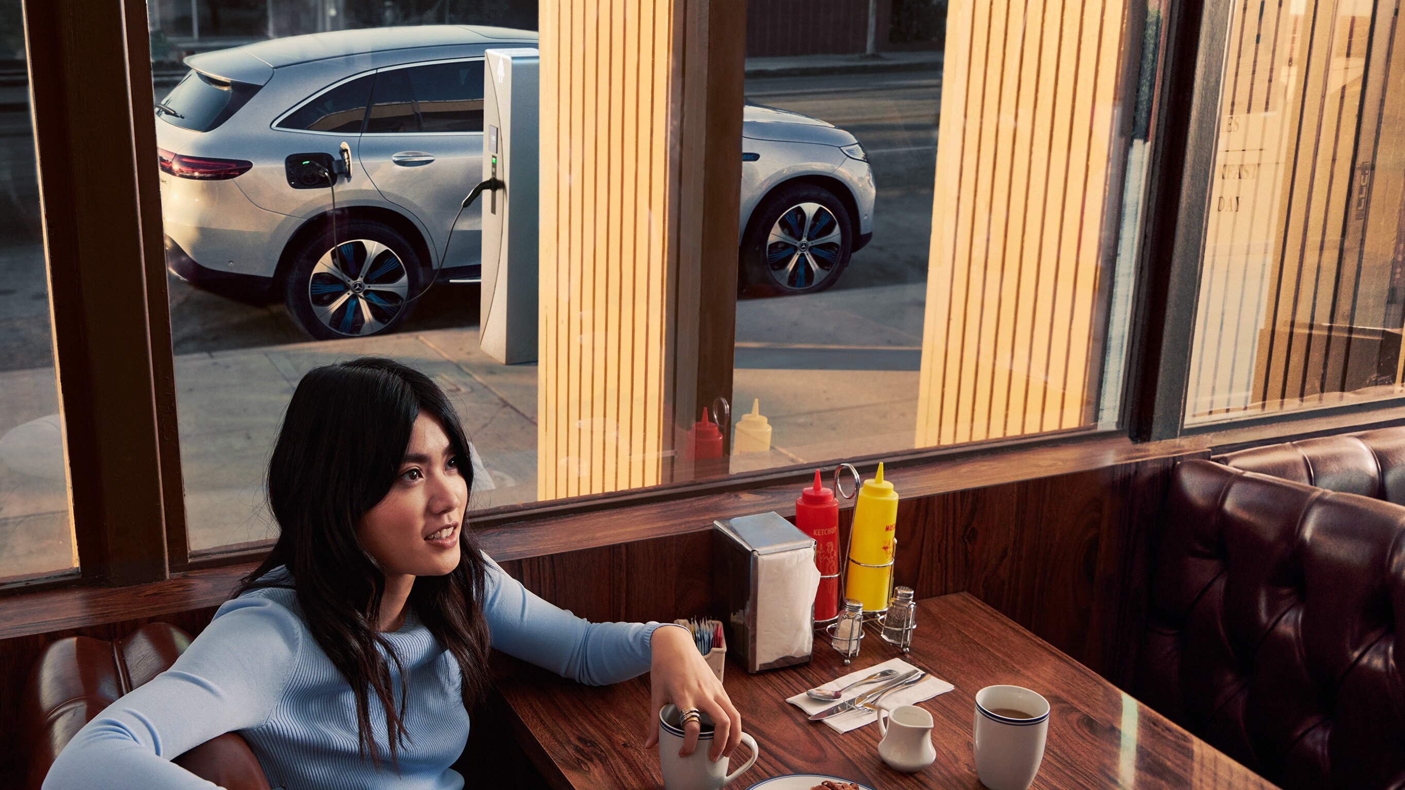 Mercedes-Benz opladen bij een publiek oplaadpunt Er wacht een persoon in het restaurant terwijl een Mercedes-Benz wordt opgeladen