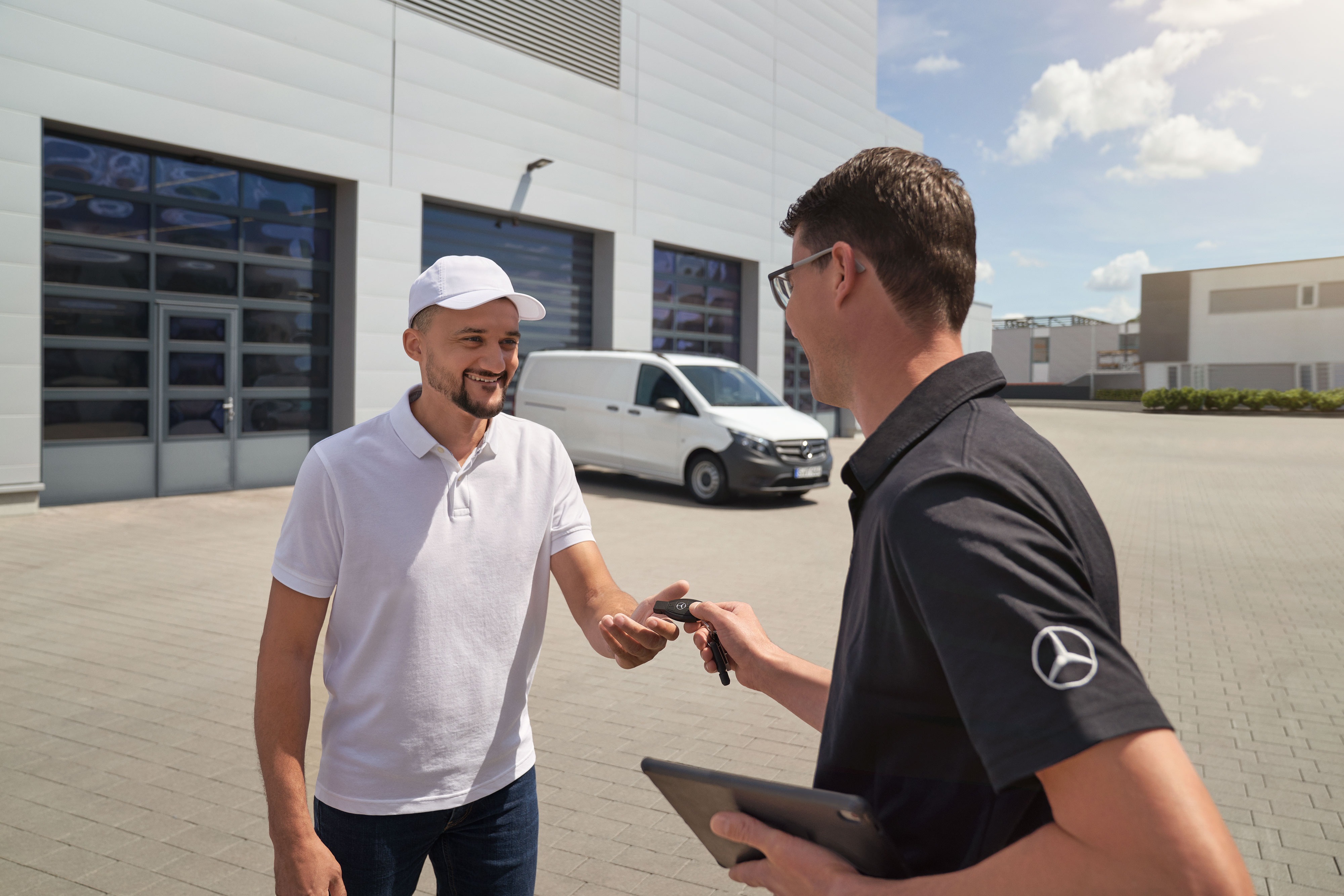 Mercedes-Benz | Confort | Service d'enlèvement et de livraison Technicien Mercedes-Benz remettant les clés à un client, avec un utilitaire léger Mercedes-Benz Vito blanc à l'arrière-plan.