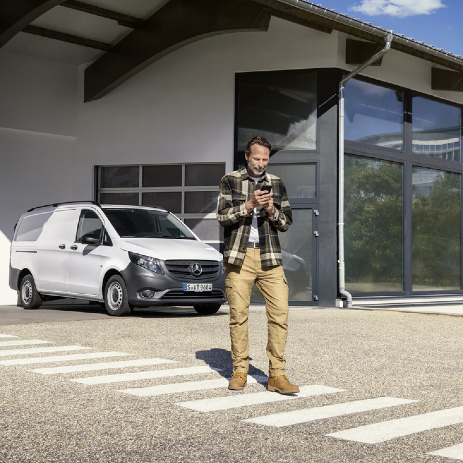 Mercedes-Benz Store | Offres digitales | Mercedes-Benz Une personne avec un smartphone devant un Mercedes-Benz Vito.