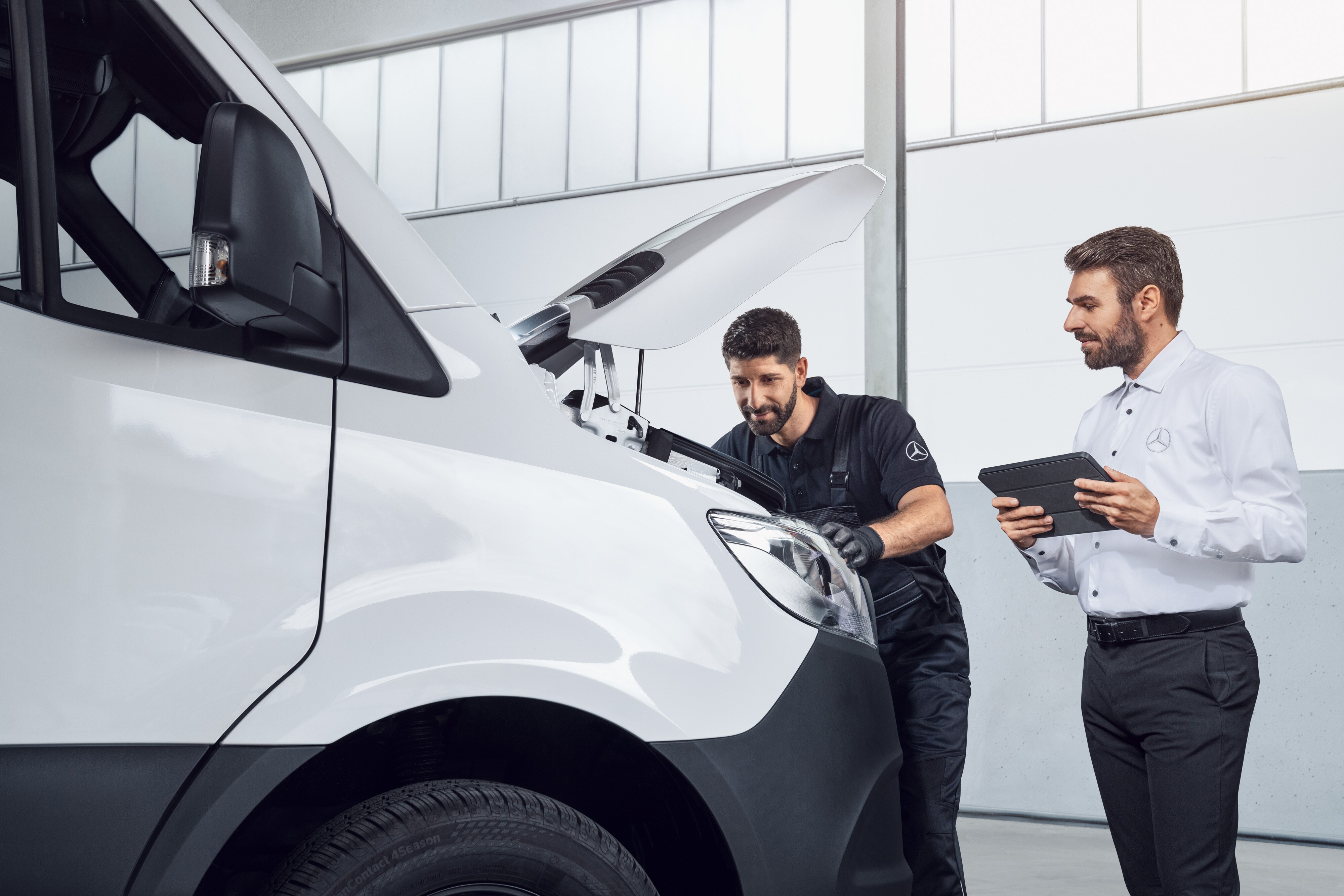 Mercedes-Benz | Pièces d'origine de qualité pour les utilitaires légers Deux hommes testant un Mercedes Sprinter avec une tablette et le capot ouvert, sujet : pièces détachées Mercedes-Benz Sprinter.